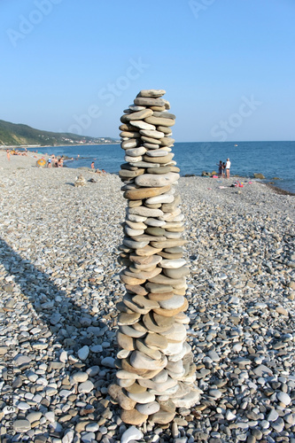 A stone pyramid on the rocky shore of the blue sea, fun on vacation photo