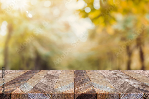 Fototapeta Naklejka Na Ścianę i Meble -  Empty old rustic wood plank table top with blur forest tree with sunlight,Autumn fall backgorund,Mock up for display or montage of product,banner for advertise on online.