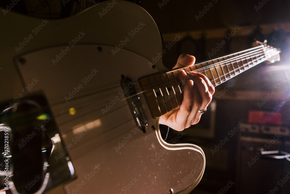Fototapeta premium Electric guitar in guitarist hands closeup. Music band rehearsal before concert, recording studio