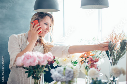 Smiling Mature Woman Florist Small Business Flower Shop Owner. She is using her telephone to take orders for her store photo