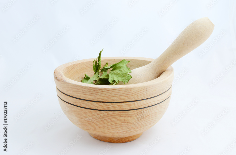 Herbs in a wooden mortar on a white background