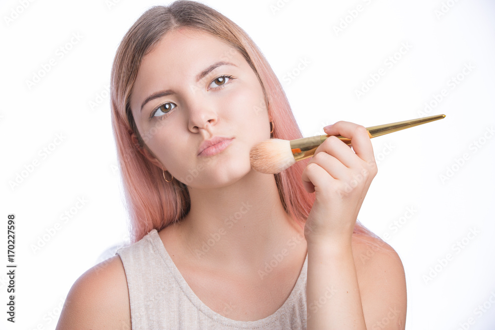 Beautiful young girl using brush to apply make up on face. Isolated on white Beautiful young girl using brush to apply make up on face. Isolated on white