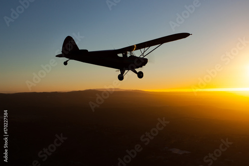 Romantic airborne evening: beautiful silhouette of a plane flying towards the setting sun