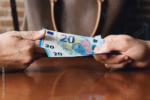 Hand of woman is giving euro money to a young man