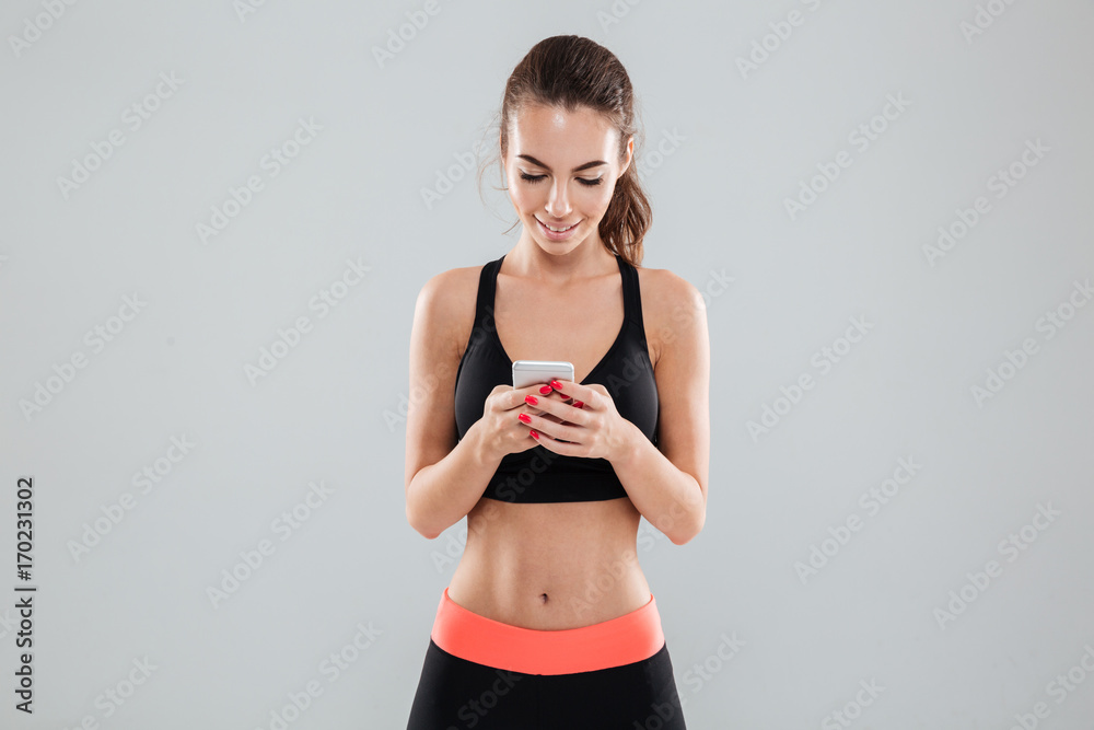 Smiling fitness woman writing message on her smartphone Smiling fitness woman writing message on her smartphone