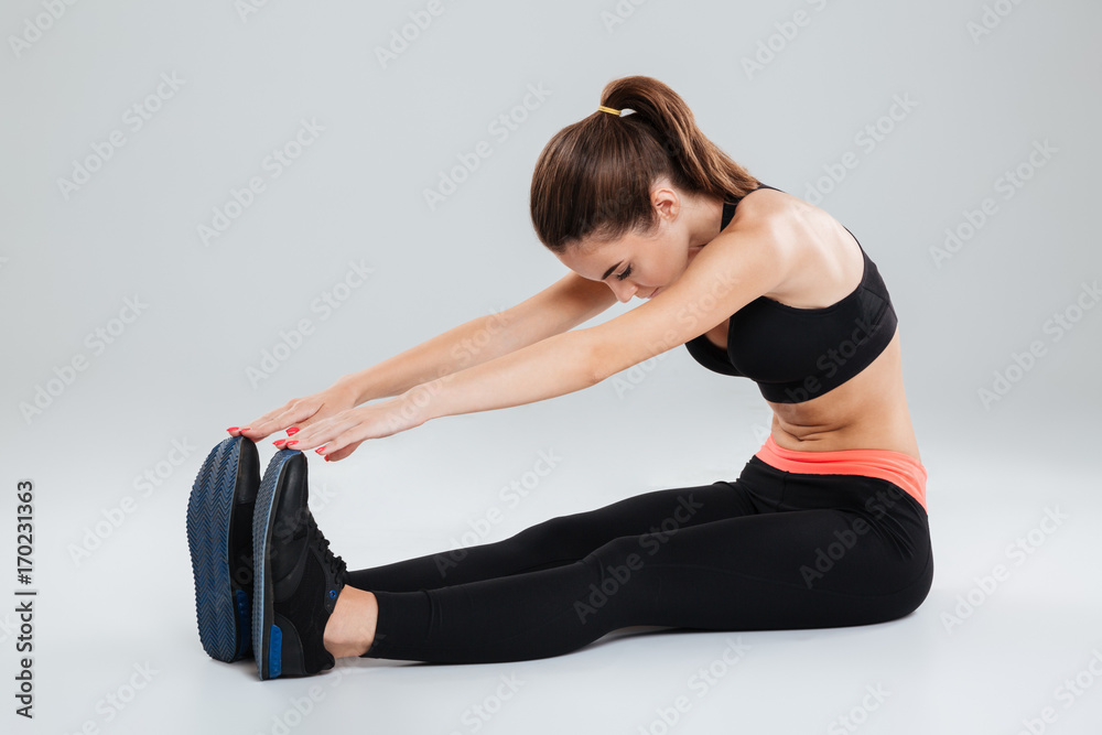 Fototapeta premium Side view of fitness woman warming up