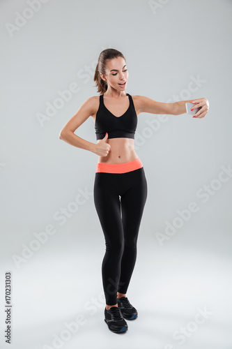 Full length picture of happy fitness woman showing thumb up