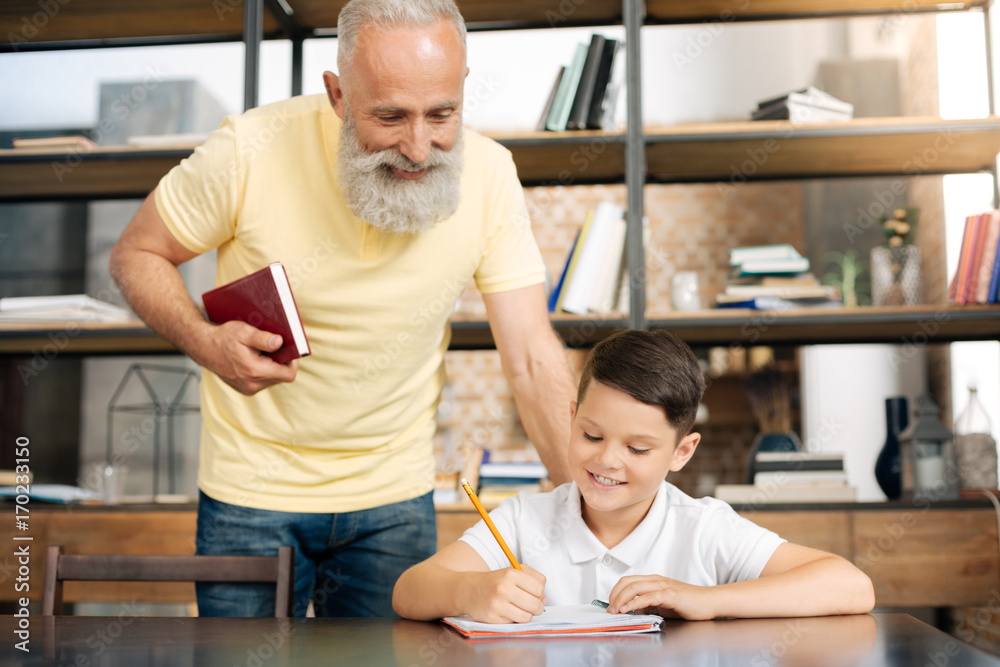 Caring grandfather checking the results of grandsons homework