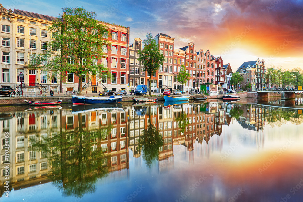 Fototapeta premium Domy nad kanałem amsterdamskim o zachodzie słońca, Holandia, panorama