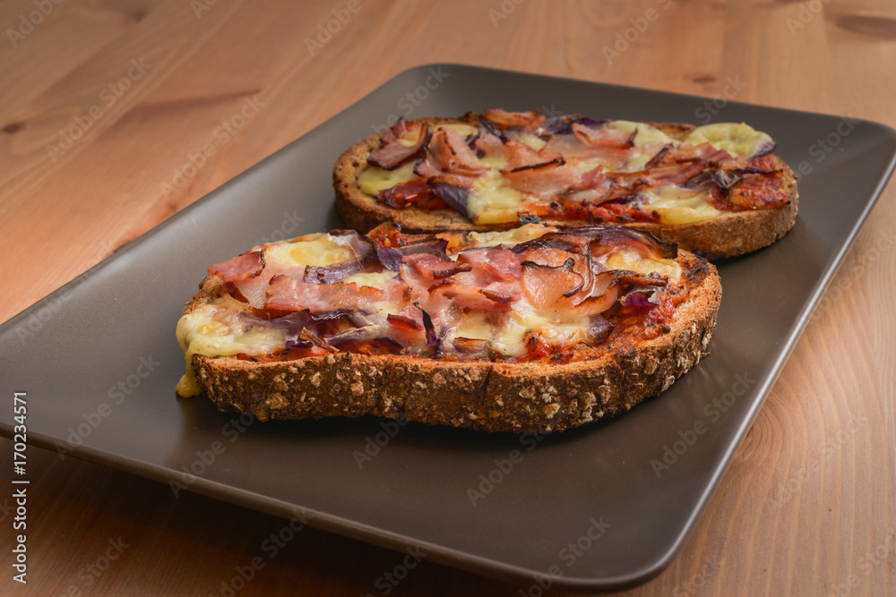Delicious seasoned savory Italian tomato bruschetta slices on a rustic wooden board garnished with fresh basil leaves.