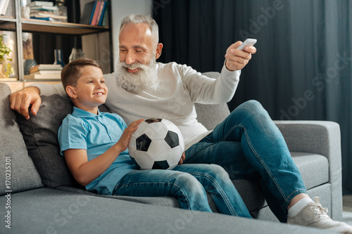 Man turning air conditioning on while watching football with grandson