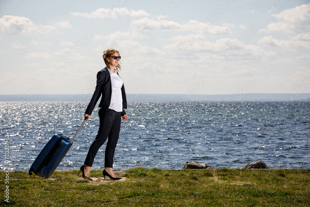 Businesswoman walking with suitcase at seaside Businesswoman walking with suitcase at seaside