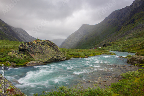 Beautiful fast river flows around the mountain in Norway.