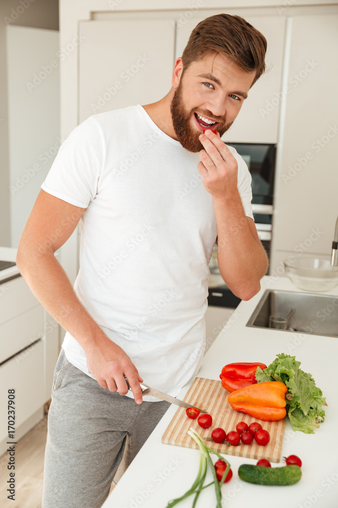 Vertical image of smiling bearded man standing near the table