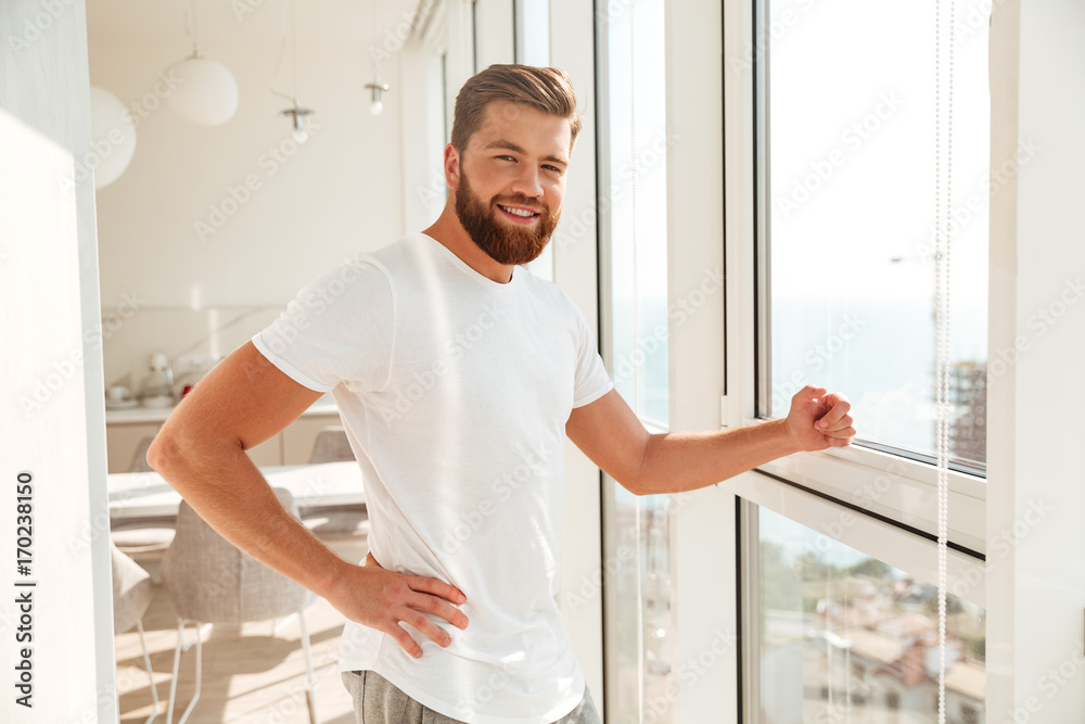 Side view of smiling bearded man standing near the window Side view of smiling bearded man standing near the window
