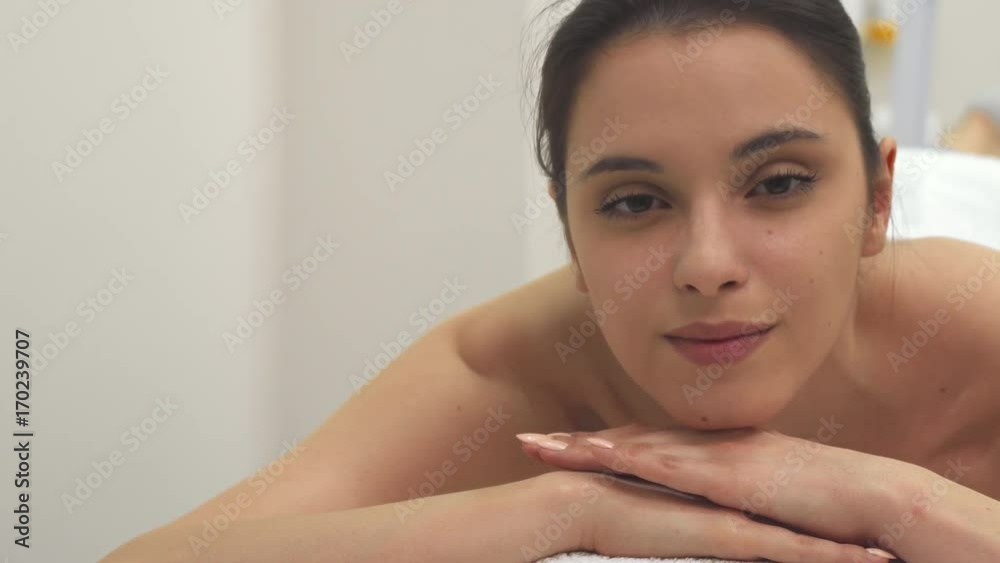Pretty brunette girl relaxing on the massage table. Close up of cute caucasian female model leaning her chin on her hands. Attractive young woman having a rest at the spa Pretty brunette girl relaxing on the massage table. Close up of cute caucasian female model leaning her chin on her hands. Attractive young woman having a rest at the spa
