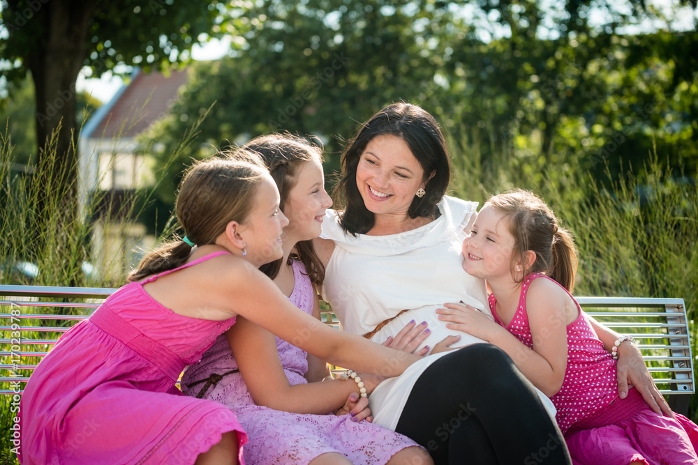 Smiling pregnant young woman with three adorable daughters