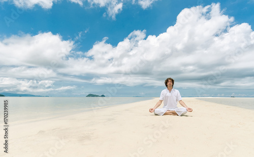 Young man meditating in Lotus position on a sandy beach