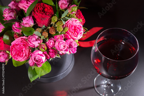 Obraz na płótnie Stylish bouquet of pink and red roses and red ribbon in a circular black box near a glass with wine w salonie