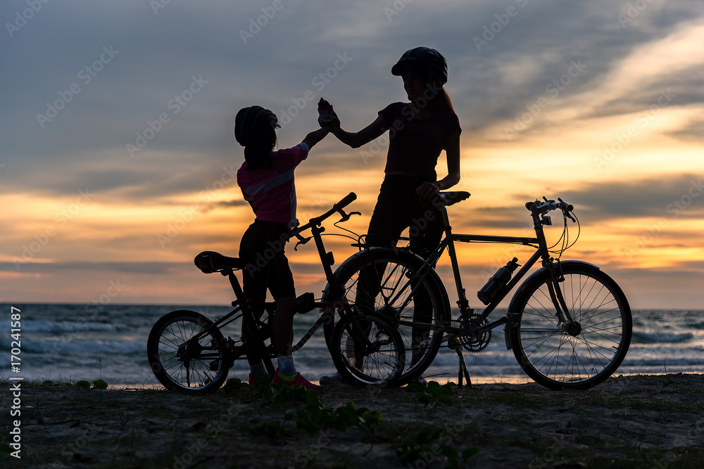 Obraz premium Biker family silhouette at the beach at sunset..