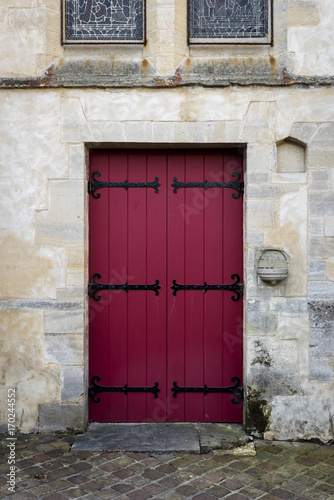 Red wooden door in an ancient stone wall © parkerspics