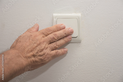 an old man turns of a light switch