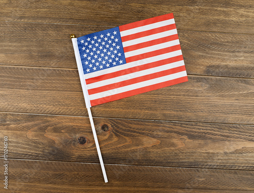 Studio shot of small bright flag of USA lying on wooden background. Copy space.