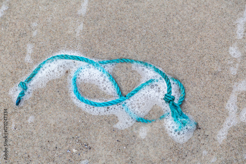 ein Stück blaues Seil liegt an einem Strand