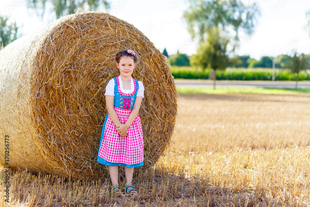 Cute little kid girl in traditional Bavarian costume in wheat field Cute little kid girl in traditional Bavarian costume in wheat field
