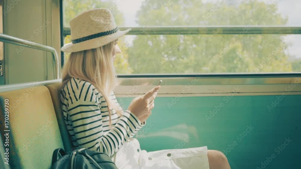 Woman tourist sitting at train and looking to mobil phone near the Eiffel tower at sunny day in Paris. Famous popular touristic place in the world.