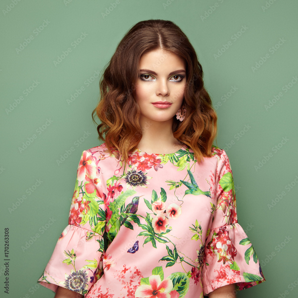 Brunette young woman in floral spring summer dress. Girl posing on a green background. Summer floral outfit. Stylish wavy hairstyle. Fashion photo. Brunette lady Brunette young woman in floral spring summer dress. Girl posing on a green background. Summer floral outfit. Stylish wavy hairstyle. Fashion photo. Brunette lady