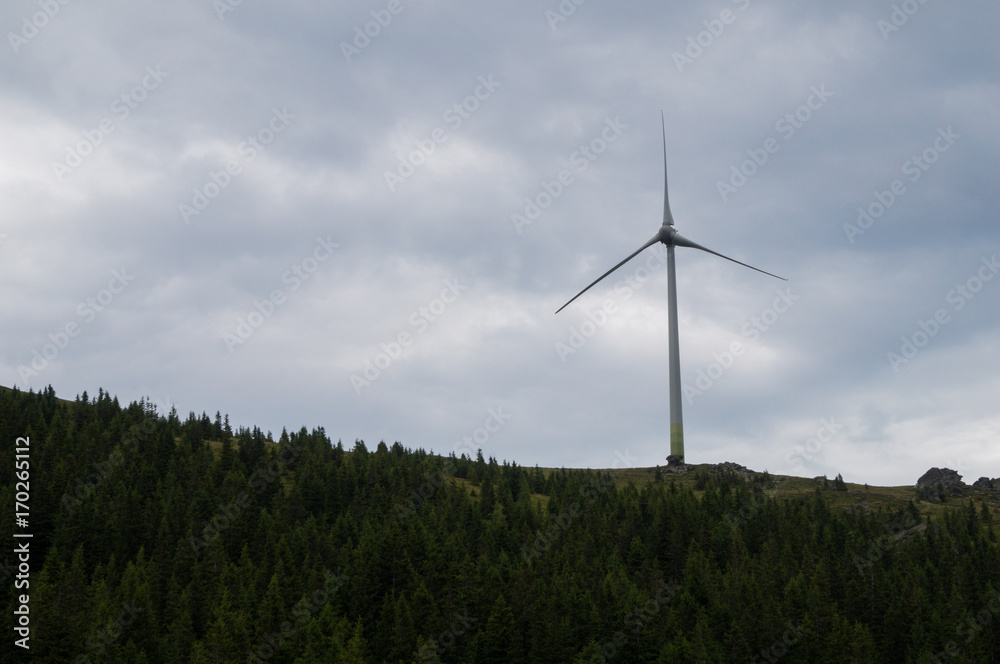 Wind turbine atop a hill on a cloudy day Wind turbine atop a hill on a cloudy day