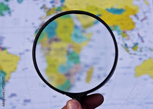 Magnifier on the background of the geographical map of the world
