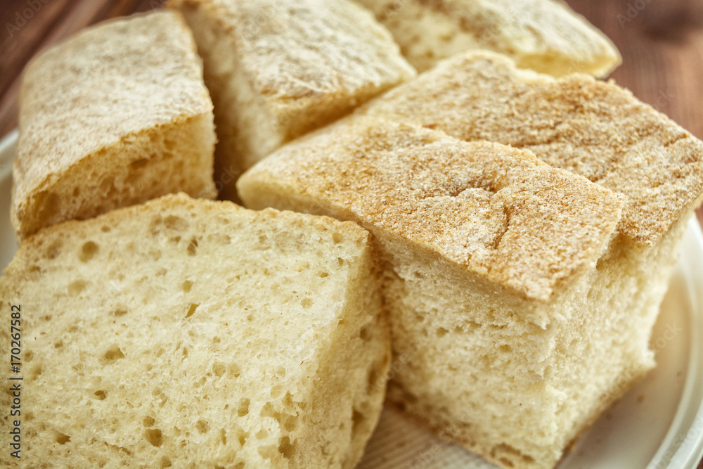 Fresh soft white bread with crust on a plate on a wooden table