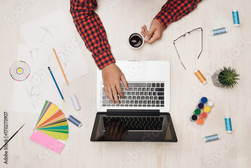 Male fashion desginer working at desk with fashion sktech. Top view. photo