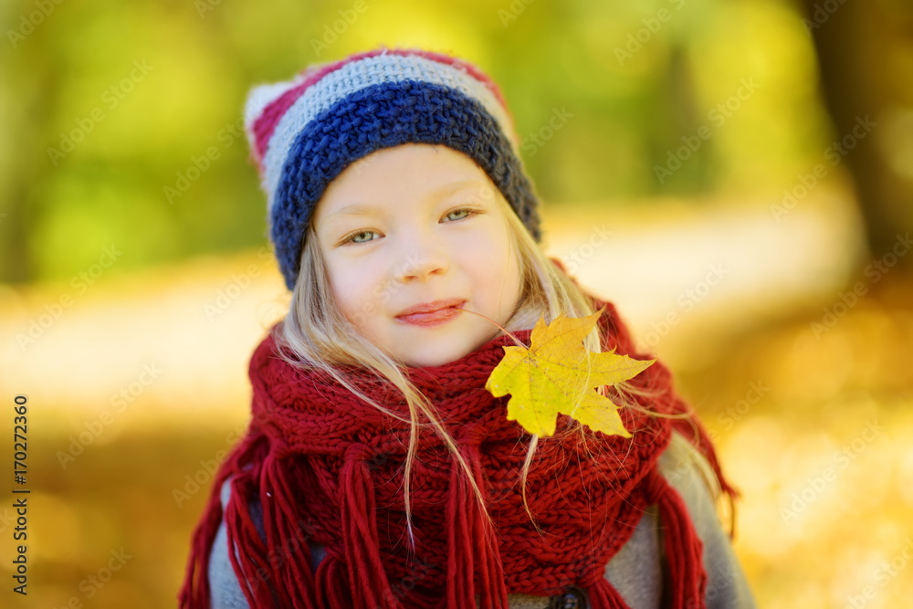 Cute little girl having fun on beautiful autumn day. Happy child playing in autumn park. Kid gathering yellow fall foliage. Cute little girl having fun on beautiful autumn day. Happy child playing in autumn park. Kid gathering yellow fall foliage.