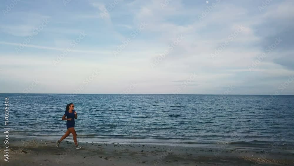 Young Woman Jogging on the Beach at Sunset. Aerial View Young Woman Jogging on the Beach at Sunset. Aerial View