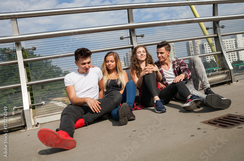 Group of friends sitting together outdoor on urban scenery © leszekglasner