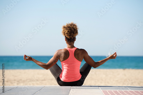 behind of young woman doing yoga exercise on seaside