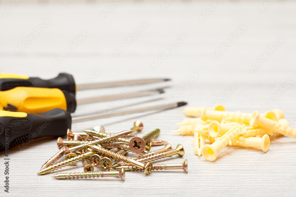 Screwdrivers and screws on white wooden background