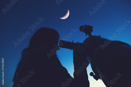 Girl looking at the Moon through a telescope.
