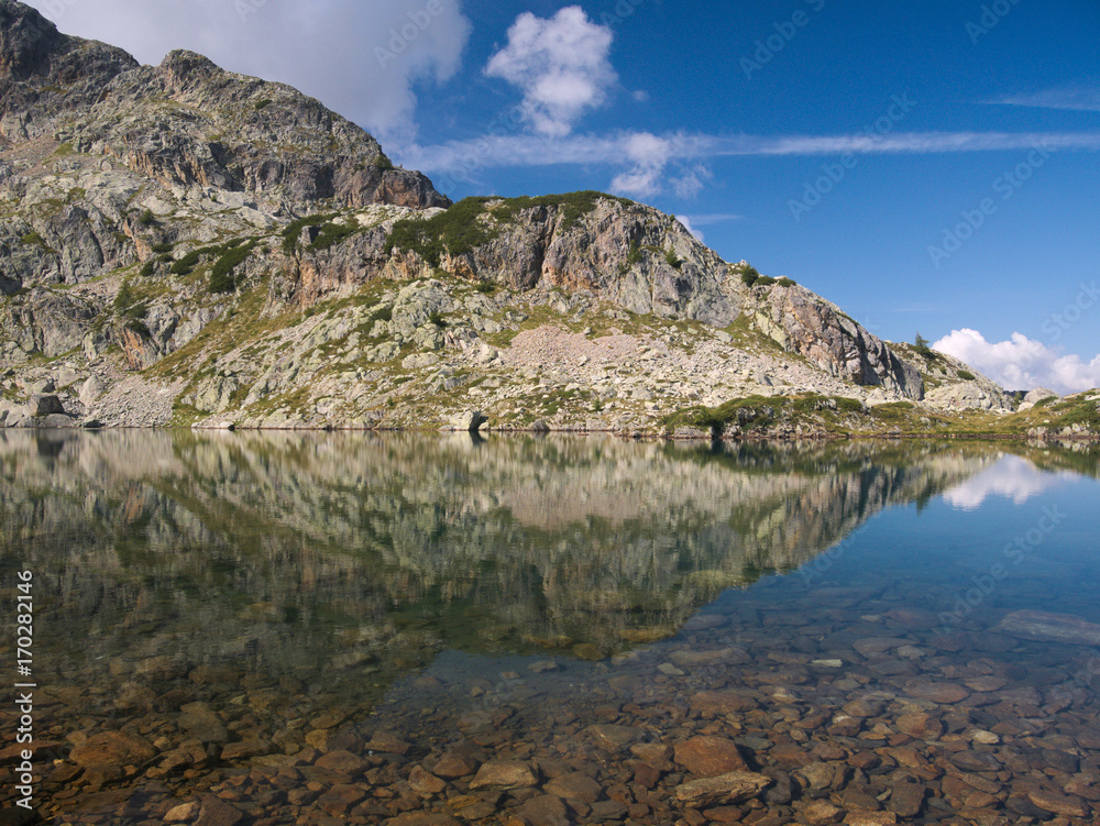 Mountains reflect on small alpine lake on the Bergamo Alps, northern Italy.