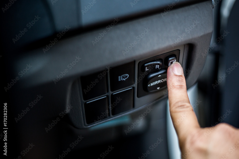 Hand pressing Close up Power window control button on car.