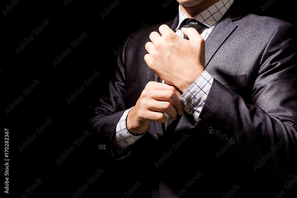 Businessman adjusting his suit on black background Businessman adjusting his suit on black background