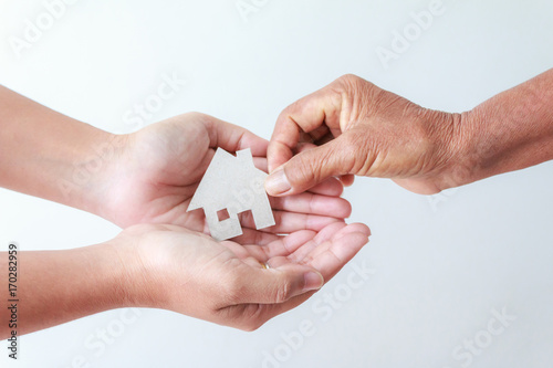 Hand of old women giving paper card house to young woman metaphor and concept for asset heritage of mother and daughter