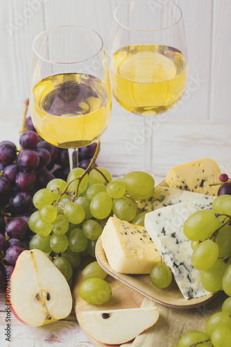 Cheese plate served with wine, fresh grapes and pears