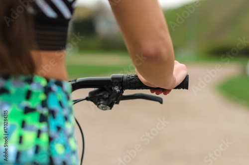 the girl the brunette in sportswear, rides a bike in the morning in the park. Close up