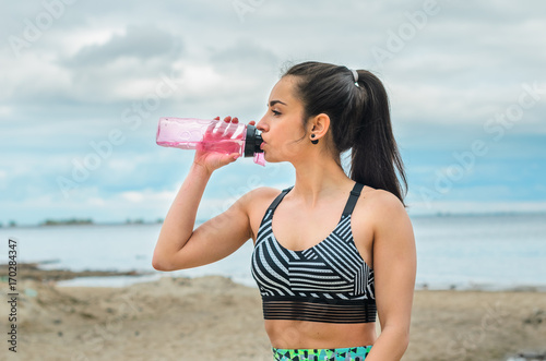 Girl beautiful brunette. Athletic body , pumped muscles. Bright colors , green ,pink . Spring , trees in bloom. She does a workout on the beach. Rides a Bicycle . makes a selfie