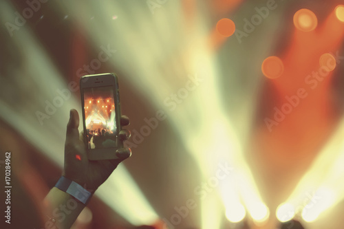 silhouette of hands with a smartphone at a concert