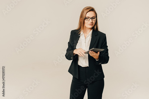 Woman in glasses holds a tablet on a light background. Place for text. Toned picture.